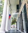 Detalle de los pórticos con columnas blancas y bandera de Texas en el porche