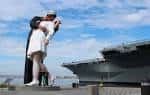 Pareja abrazándose frente al USS Midway en el muelle de Broadway, San Diego