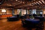 Interior del salón de eventos con mesas redondas y techo de vigas de madera