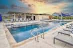 Piscina comunitaria al atardecer con tumbonas y estructura de sombra
