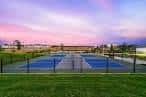 Canchas deportivas exteriores con césped circundante bajo cielo crepuscular