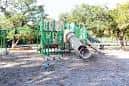 Área de juegos infantiles con toboganes verdes en el parque