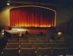 Interior del auditorio con cortinas rojas y butacas vacías