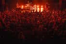 Concierto en vivo con el público lleno y luces rojas en el escenario