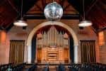 Interior del salón principal con órgano histórico y bola de discoteca colgando