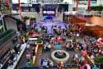 Plaza central de KC Live! con mesas, gente y escenario durante el día