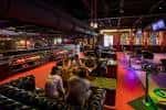 Interior del local con pistas de bolos, mesas y ambiente festivo con luces de colores