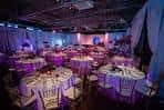 Sala de eventos decorada para una boda con mesas redondas y luces de ambiente