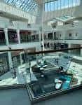 Vista interior del centro comercial con atrio de cristal y múltiples niveles