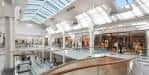 Ampio pasillo interior del centro comercial con techos de vidrio y tiendas a ambos lados