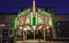 Fachada nocturna del Aladdin Theater con letrero neón verde encendido
