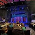 Interior del auditorio durante una función teatral con público infantil y escenario iluminado