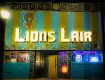 Fachada nocturna del Lion's Lair con letrero iluminado