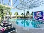 Piscina al aire libre del hotel con tumbonas y decoración artística en la pared