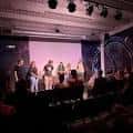 Escenario del teatro con elenco en presentación de comedia