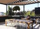 Vista del rooftop de Jackie's con mesas y sillas bajo una pérgola