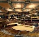 Interior del auditorio mostrando la acústica diseñada con paneles curvos y iluminación cálida