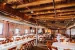 Interior del salón de eventos The Hayloft con mesas redondas y techos de madera