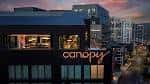 Fachada nocturna del hotel con el logo 'canopy' iluminado