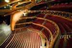 Interior del auditorio principal con butacas rojas y diseño curvo en madera