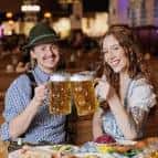 Pareja sonriente brindando con jarras de cerveza en el interior del restaurante