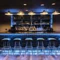 Bar interior del teatro con estantería iluminada y taburetes modernos