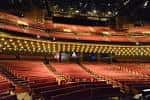 Interior del Grand Ole Opry House con butacas rojas y escenario iluminado