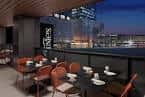 Terraza con mesas y sillas al atardecer con vista a la ciudad