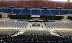Interior del coliseo con gradas y escenario listo para eventos