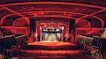 Interior del auditorio con escenario iluminado en rojo y butacas