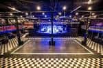 Interior del salón de eventos con escenario iluminado y suelo a cuadros