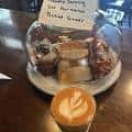 Plato de postres artesanales acompañado de un café con arte latte