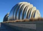 Vista exterior del Kauffman Center con su icónica fachada de acero inoxidable bajo cielo azul