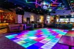 Interior del bar con pista de baile iluminada y ambiente disco