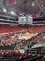 Interior del arena durante un evento deportivo con gradas rojas y tablero de puntuación