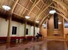Interior del Woodlawn Hall con techo de vigas de madera y piano en el escenario