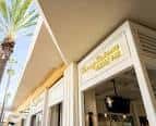 Fachada exterior del Tommy Bahama Marlin Bar con palmeras y letrero dorado