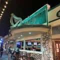 Fachada nocturna de The Harp con su distintivo letrero iluminado y arpa verde