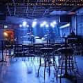 Interior del Larimer Lounge con escenario iluminado y mesas vacías