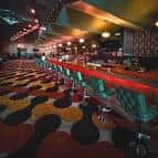 Bar retro en el Eastside Bowl con taburetes verdes y alfombra de patrones circulares