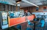 Interior del Café Corazón con mostrador naranja y sillas azules