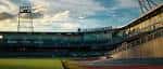 Ángulo exterior del estadio mostrando las gradas y la torre de iluminación durante el atardecer