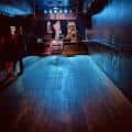 Escenario vacío con iluminación azul y piso de madera en Hi-Dive