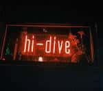 Letrero de neón rojo con el nombre 'hi-dive' en la fachada nocturna