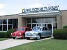 Fachada exterior del Lane Motor Museum con dos coches vintage en la entrada