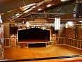Interior del escenario principal con piso de madera y cortina negra