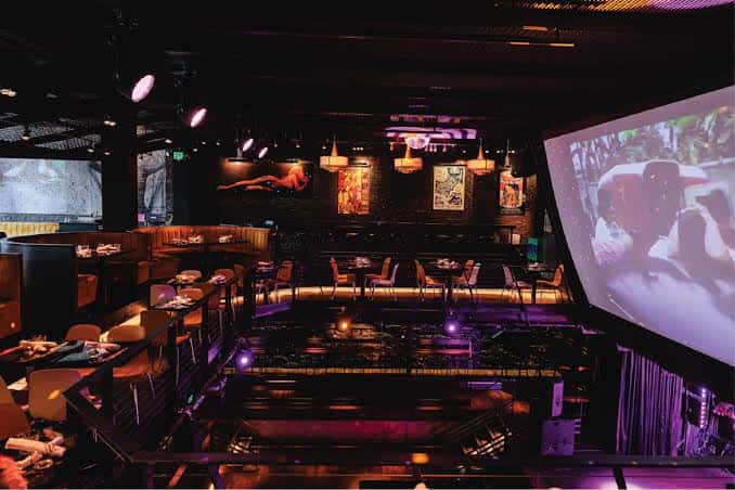 Espacio vacío del venue preparado para eventos, mostrando mesas, escenario y pantallas