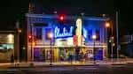 Fachada nocturna del Bluebird Theater iluminada con neón azul y ambiente urbano