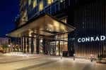 Fachada nocturna del Conrad Nashville con entrada iluminada