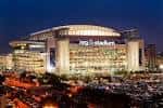 Vista nocturna del NRG Stadium con iluminación exterior y estacionamiento